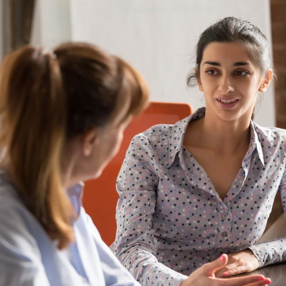 Indian businesswoman speaking to colleague or hr during job interview, young professional hindu woman manager consulting client or explaining giving advice teaching at business office meeting